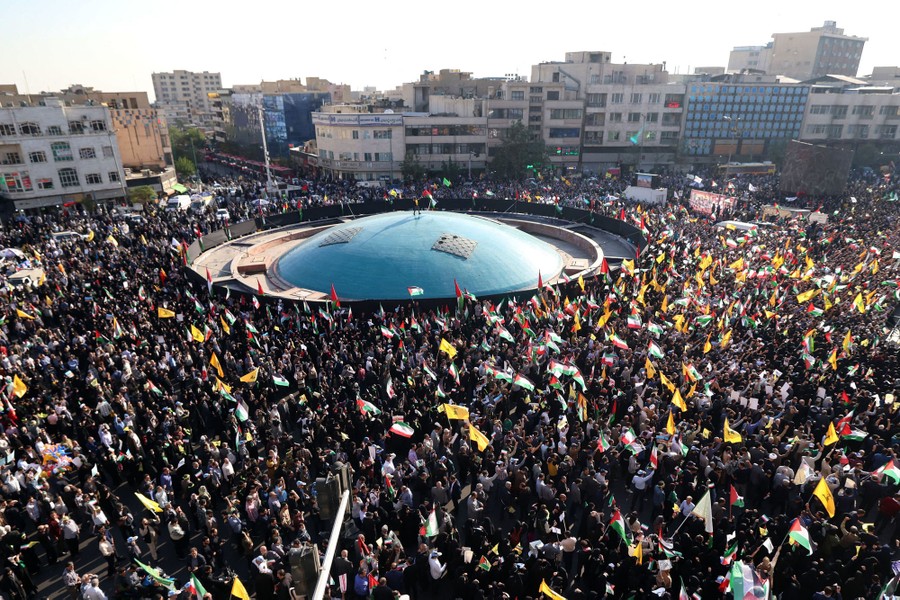 A large crowd of pro-Palestine protesters gathers in a city square.