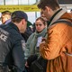 A traveler shows a police officer something on his phone while standing in line at an airport