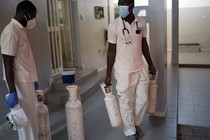 Two people who work for an emergency mobile service in Dakar, Senegal, carry oxygen tanks in a hallway