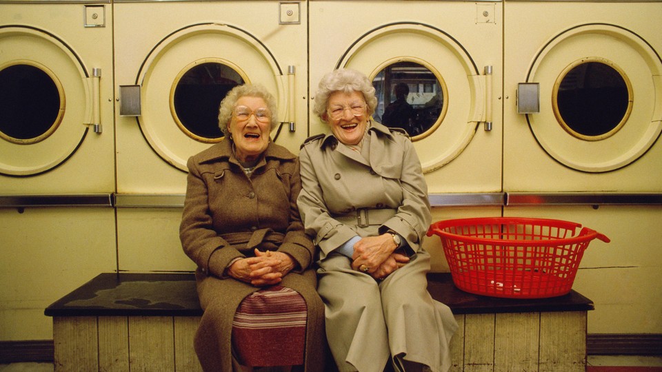 Two older women smiling and posing at a laundromat