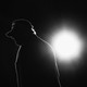 Donald Trump in silhouette, backlit by a single circle of light
