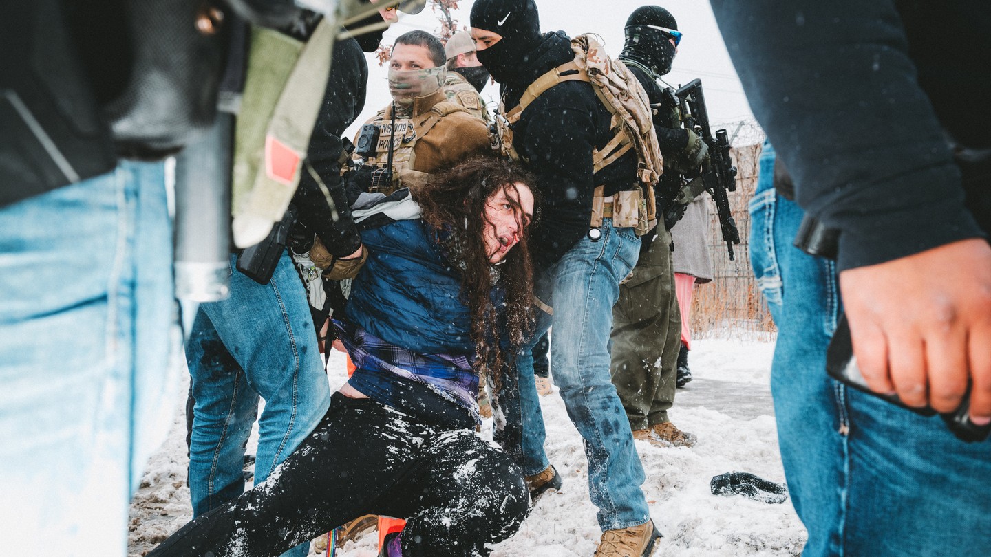 A man being brought to the ground by a group of ICE agents
