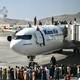Afghan citizens climbing atop a plane at Kabul airport.