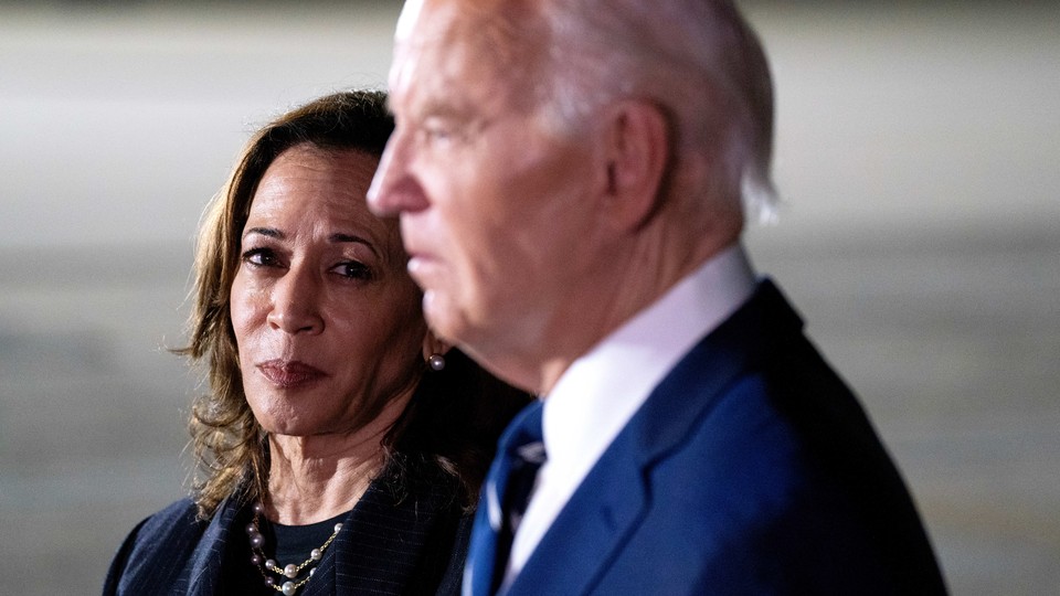 Photograph of Joe Biden, slightly blurred in the foreground, and Kamala Harris in focus in the background looking at Biden.
