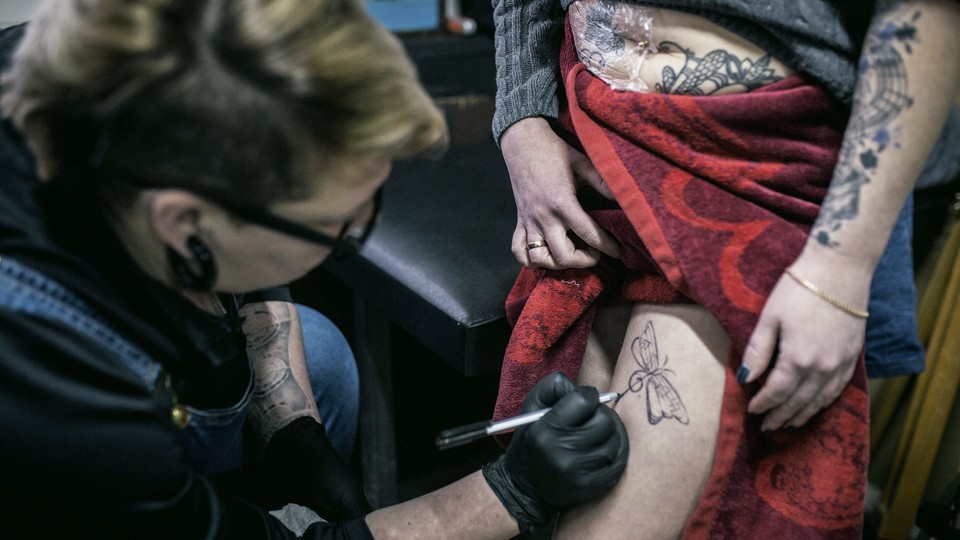 A woman gets a tattoo to conceal a scar from a domestic violence attack in Ufa, Russia.
