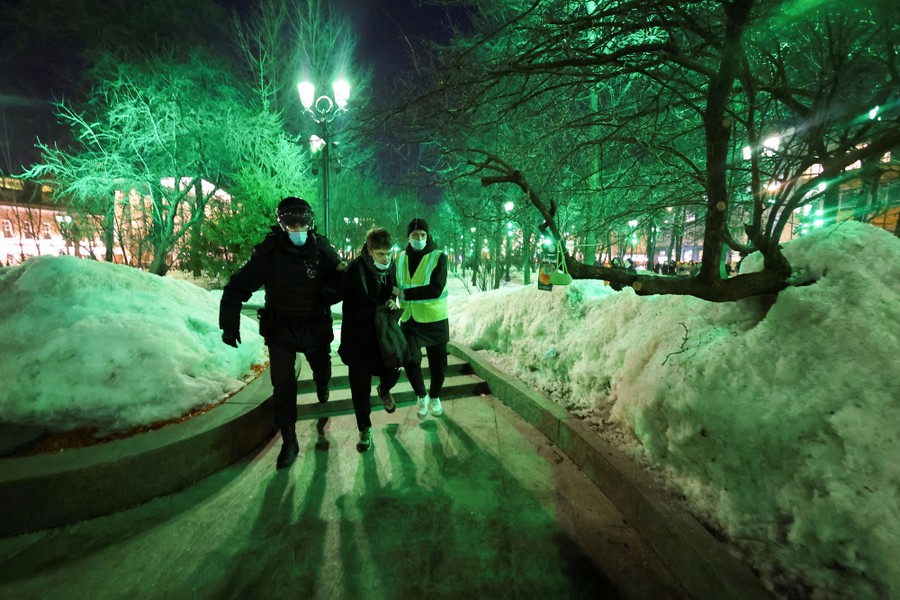 A person is detained by police officers in a park.