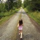 a little girl in a pink and bathing suit walks on a path in the woods