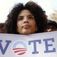 A woman holding a "Vote" sign with the Obama campaign logo as the "o"