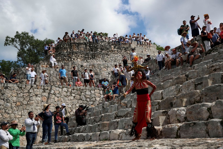 A crowd gathers atop stone steps at an archeological site in Mexico.