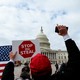 A photo of a man holding a "Stop the Steal" sign in front of the Capitol.