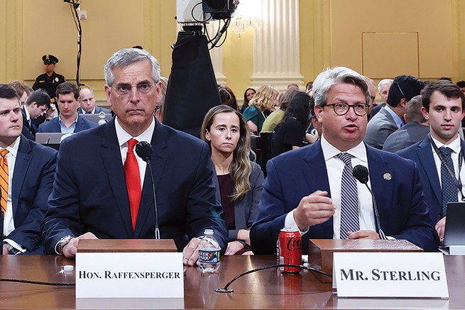 photo of two men wearing business suits at hearing