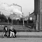 Two children sitting on the sidewalk alone