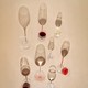 Photograph of eight partially full wine glasses casting shadows on a beige background