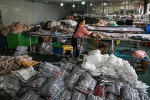 a woman works in a warehouse with clothes piled up