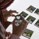 A woman uses a magnifying glass to look at thumbnails from Seeking Mavis Beacon