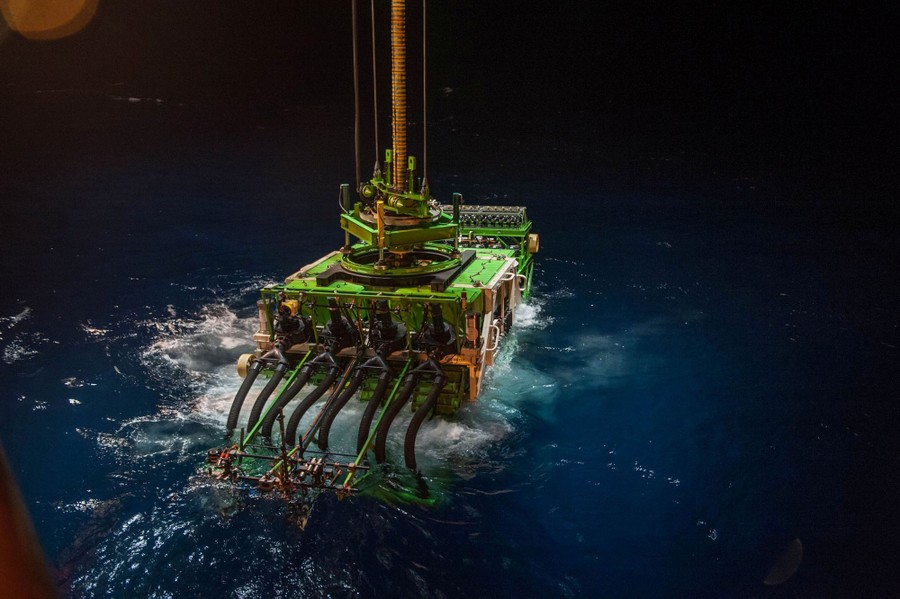 A large industrial robot is lowered into the ocean.