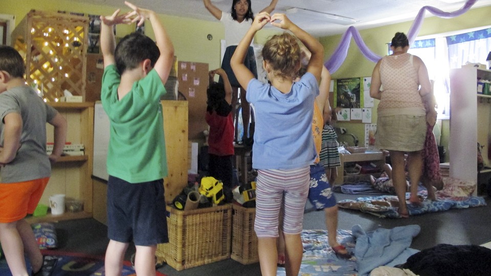 A teacher instructs preschool students in yoga.