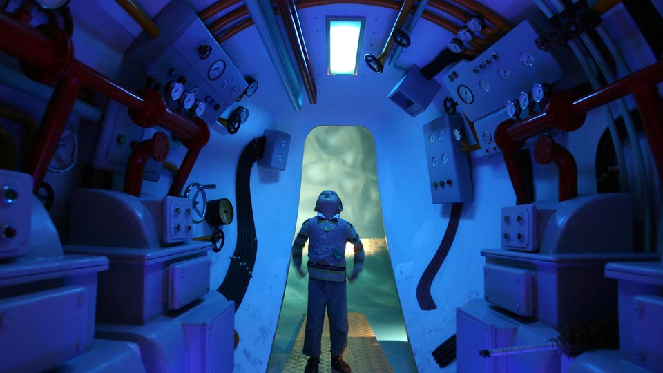 A boy stands in a submarine, looking up. 