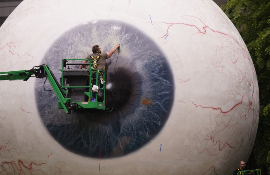 A person works in front of a giant sculpture of an eyeball.