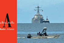A speedboat of the Trinidad and Tobago Coast Guard patrols as the USS Gravely warship is seen at a distance from Port of Spain