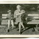 A vintage photo of a woman and a child reading books on a bench