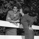 Black and white photo of two women gossiping across a fence