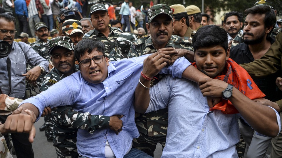 Security personnel grab student protesters during a demonstration.