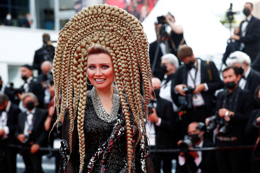 A performer with extravagant hair decorations poses for photographers.