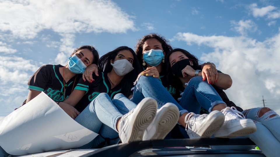 Four graduating high-school students wearing face masks.