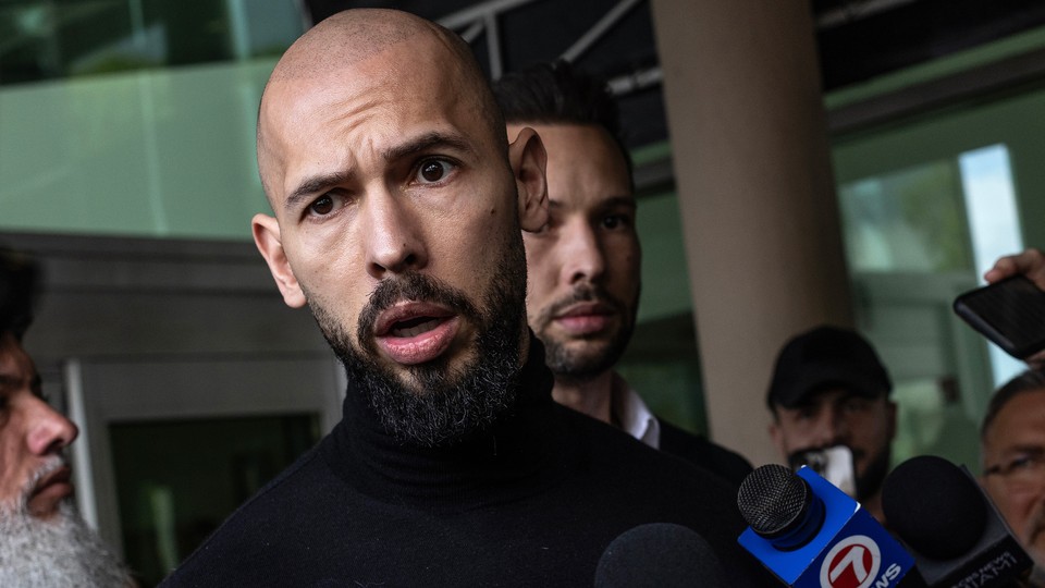 Photo of Andrew Tate speaking to press and Tristan Tate behind him