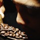 A photo of a person smelling roasted coffee beans next to a photo of Robusta coffee cherries
