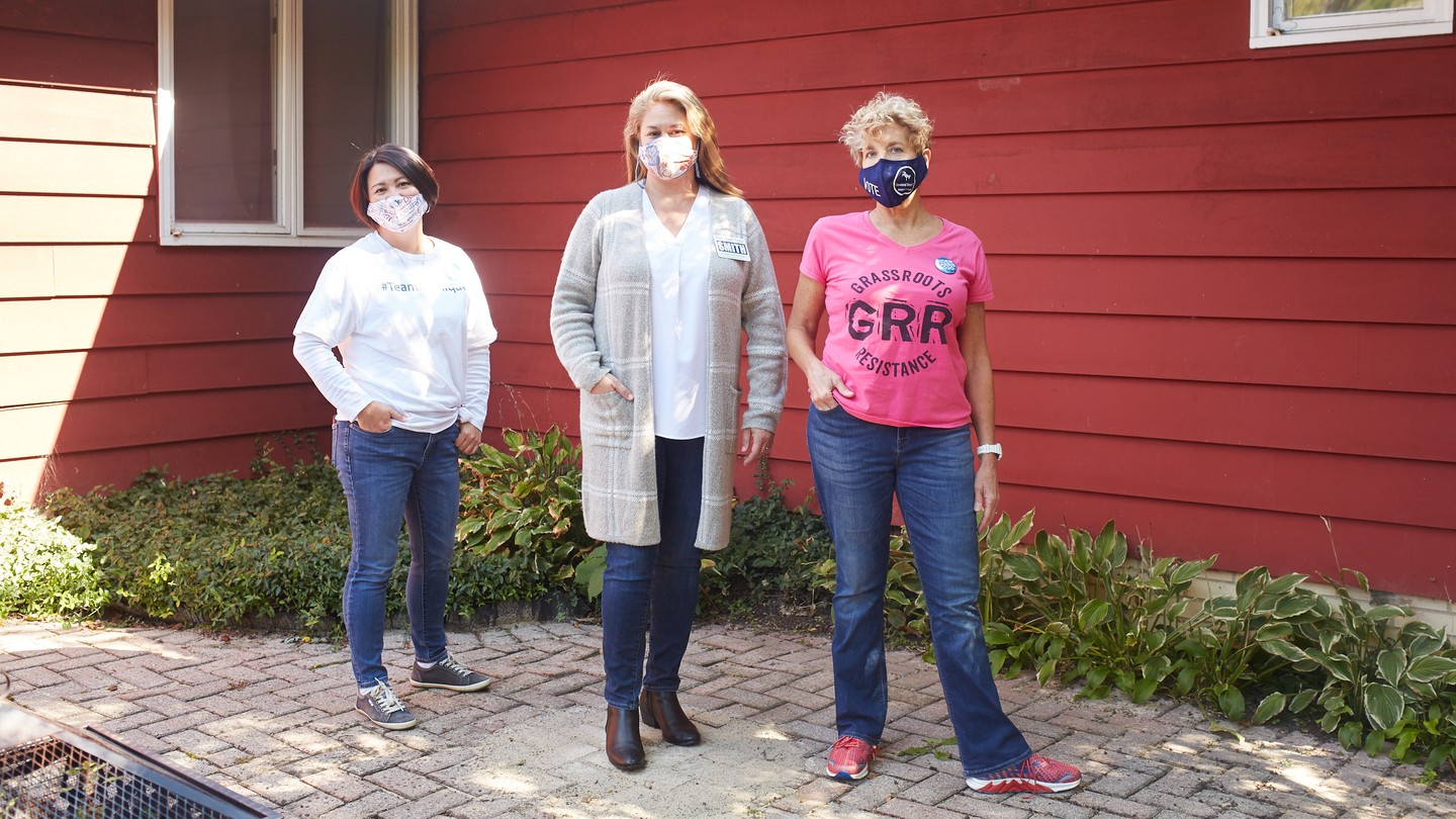 GRR's leader, Susan Polakoff Shaw, stands with two other women wearing jeans outside a red wood-paneled house.