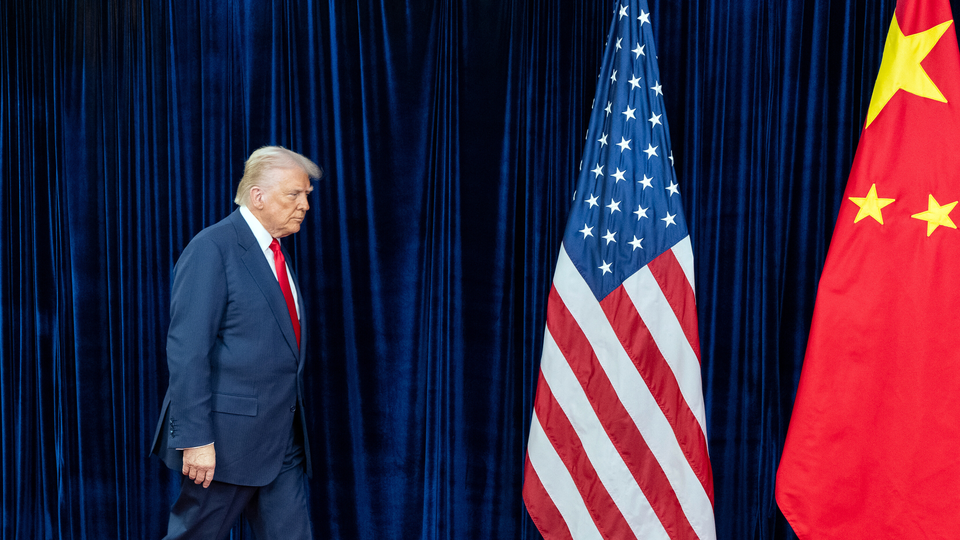 Photograph of Donald Trump walking on stage toward American and Chinese flags