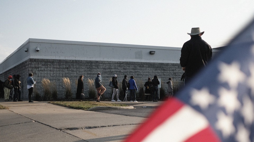 voters lining up outside of voting location with U.S. flag