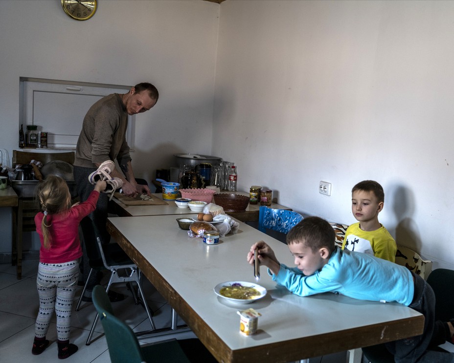 a man serves food at a table with kids