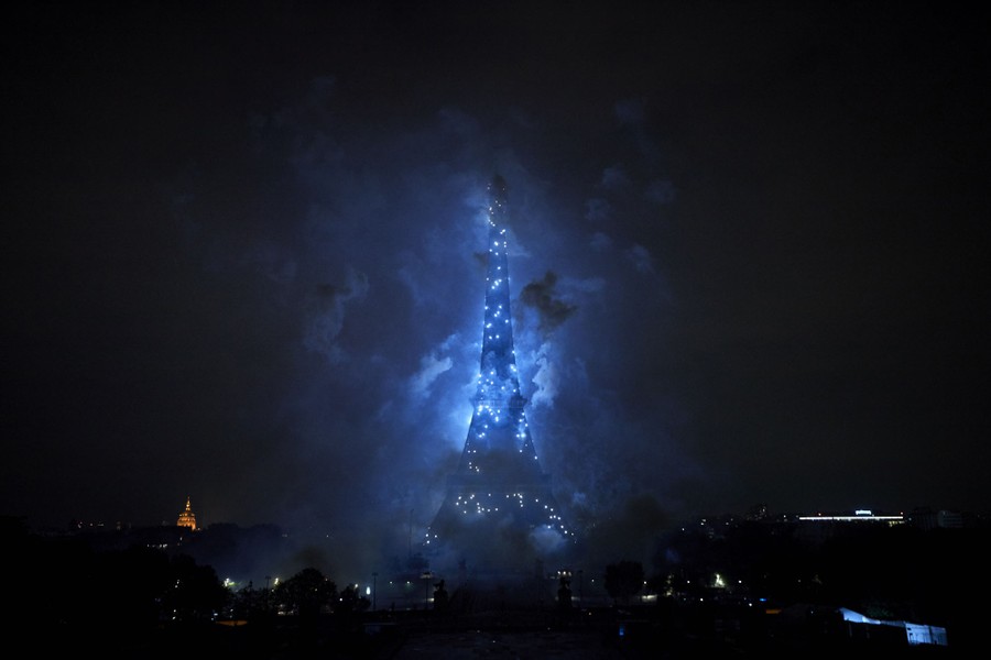 Fireworks erupt around the Eiffel Tower.