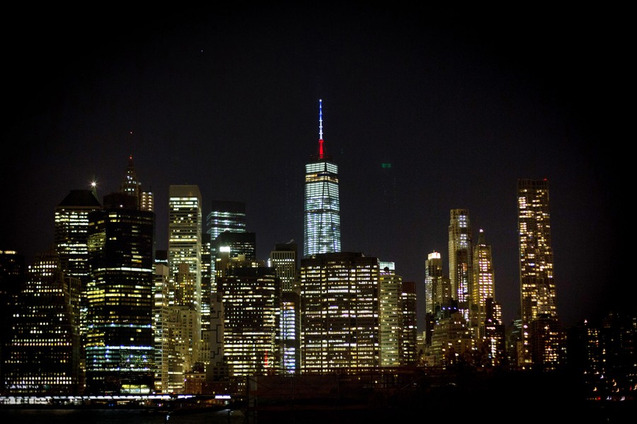 The One World Trade Center spire is lit blue, white, and red.