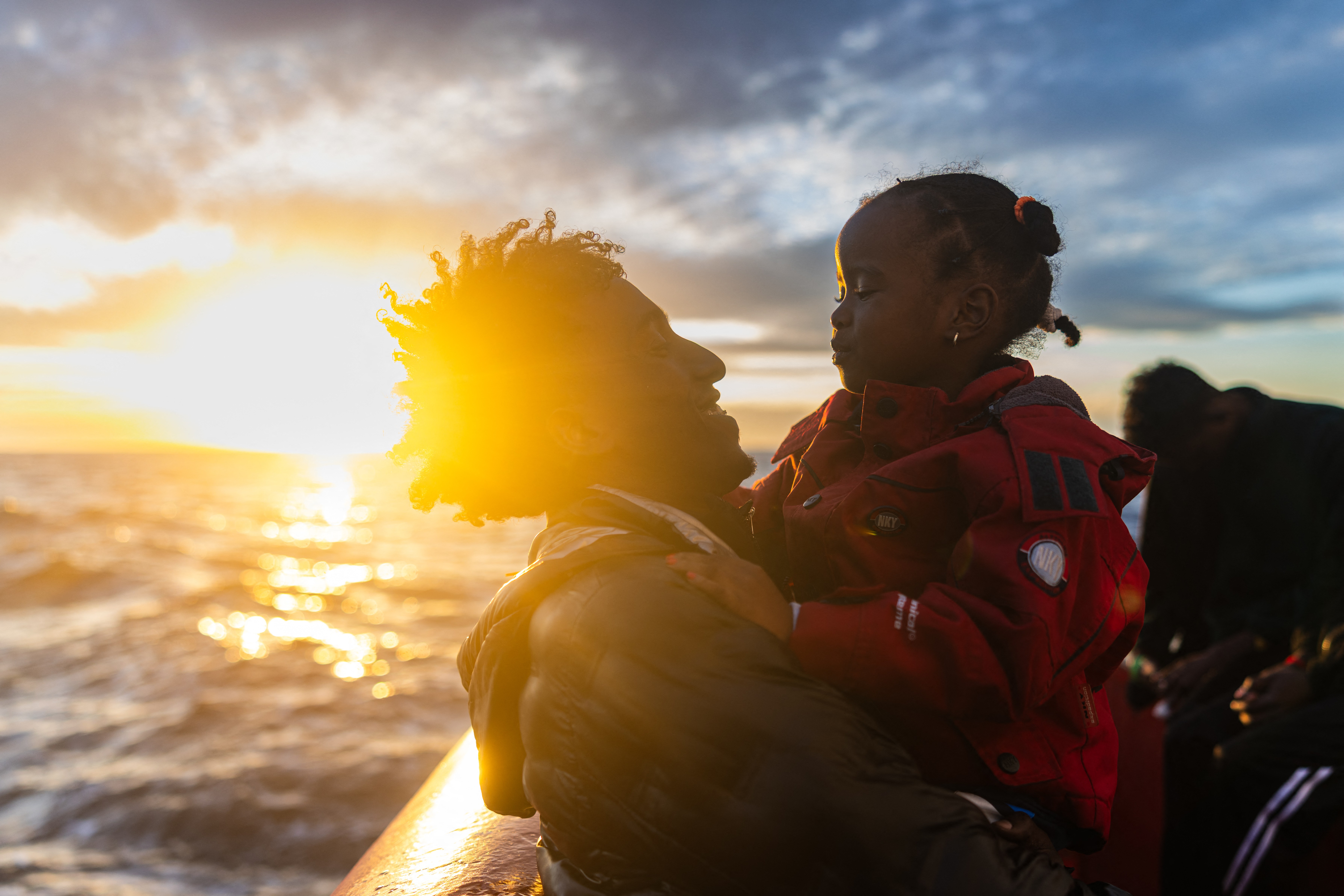 A migrant plays with a little girl aboard a rescue ship in the Mediterranean.