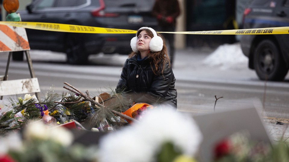 A woman wearing earmuffs attends a makeshift memorial for Alex Pretti on January 26, 2026, in Minneapolis, and looks up into the distance as though she is crying