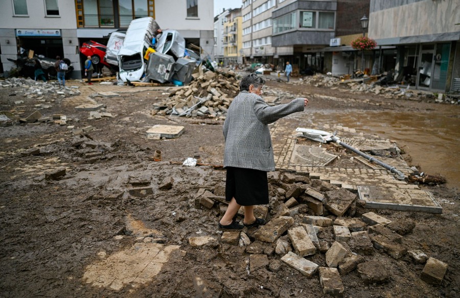 A woman walks through a heavily damaged street.