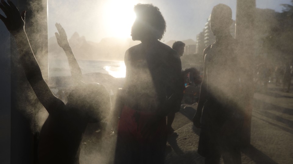 People cool off at a cooling station on a hot winter day on Ipanema beach.