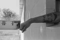 An imprisoned person stretches their arm out of a window.