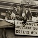 Elizabeth Wolstenholme Elmy by a banner that reads "England's Oldest Militant Suffragist Greets Her Sisters"