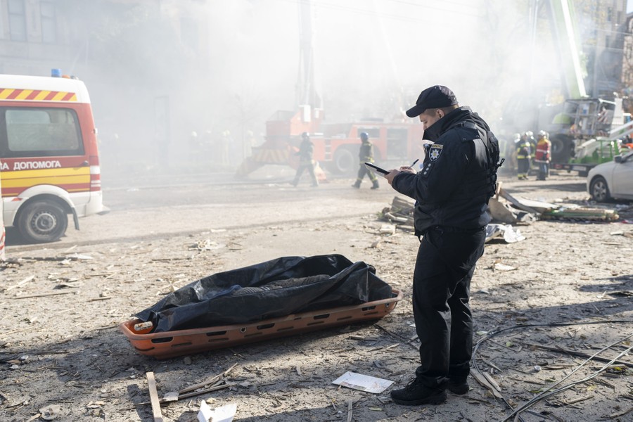 A police officer stands in a street, next to the body of a man killed after a drone strike.