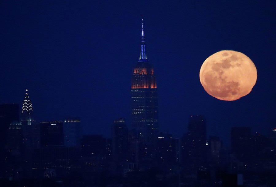 The full moon rises behind the New York City skyline, including the Empire State Building, center, and the Chrysler Building, left, as seen from downtown Newark, New Jersey, on March 12, 2017.