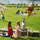 A birthday party in a park on a sunny day, with people relaxing in the background an urban skyline in the distance