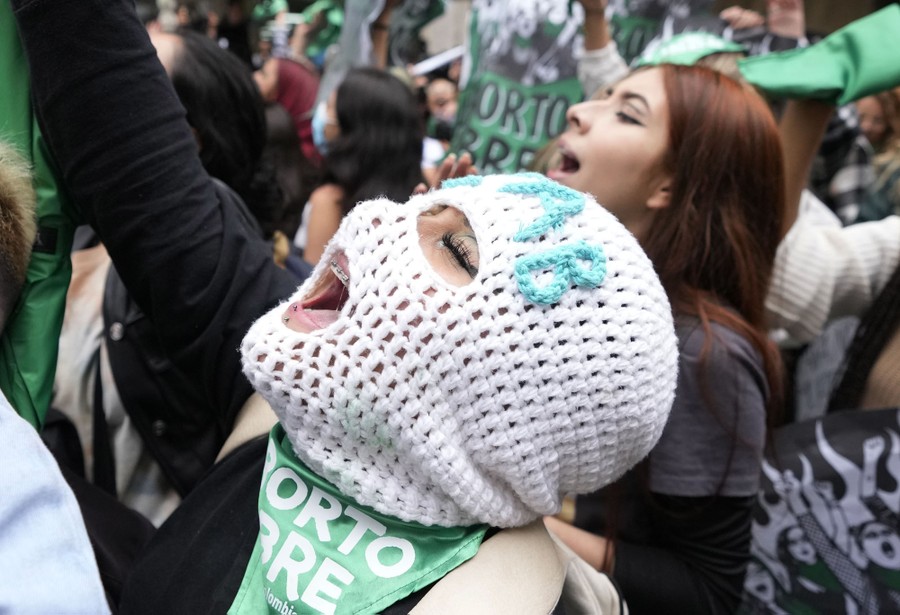 A person in a mask joins with others celebrating during a demonstration.