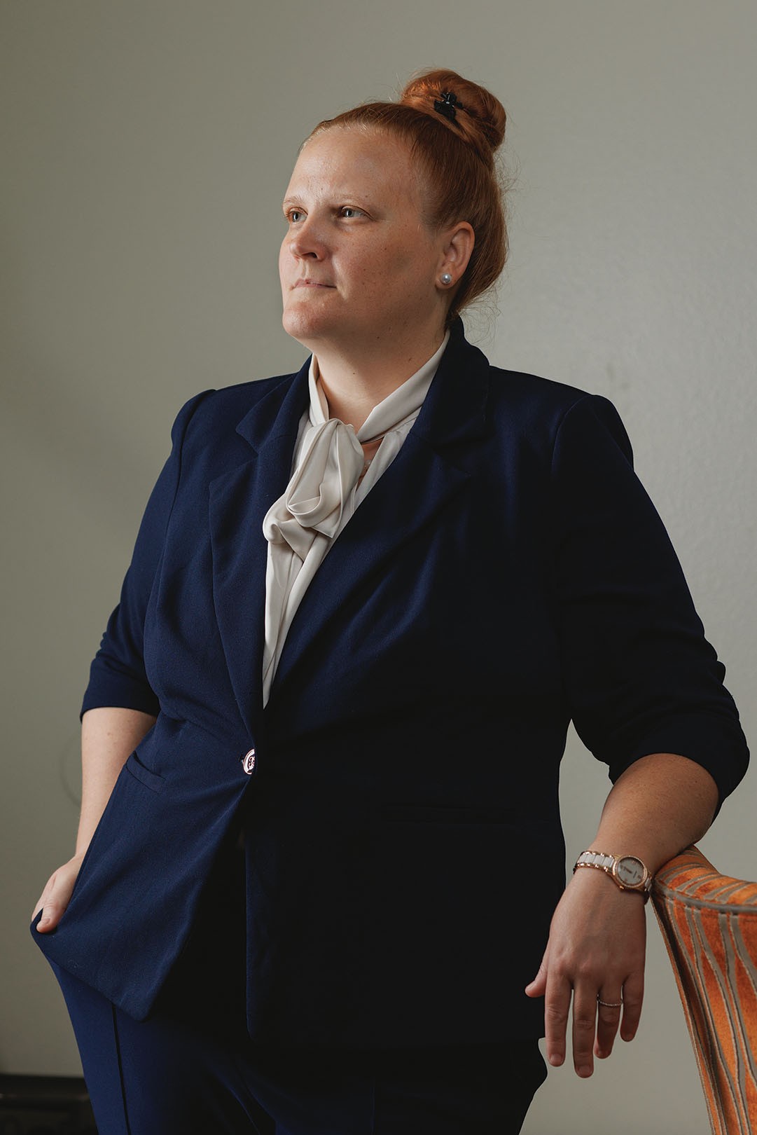 photo of woman with hair up in bun wearing silk shirt and blue suit