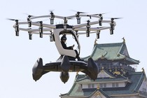 A person flies a small drone-like aircraft near a Japanese castle.
