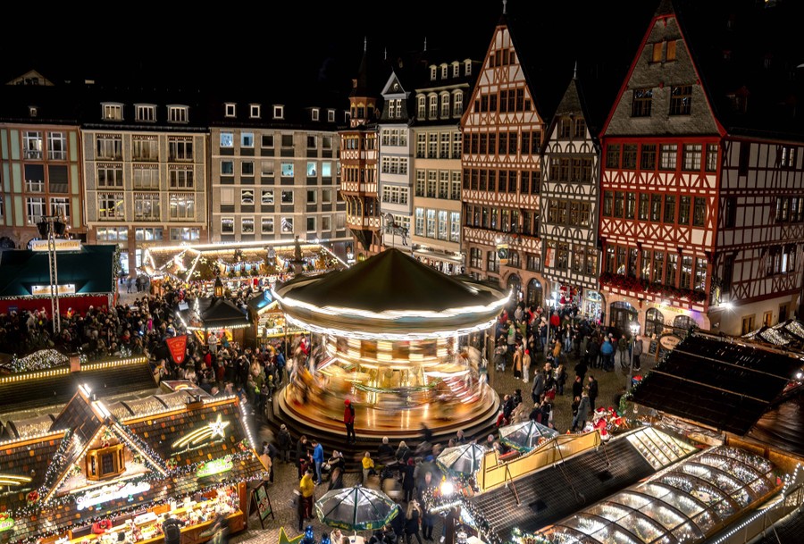 Lights illuminate a traditional Christmas Market with a merry-go-round.
